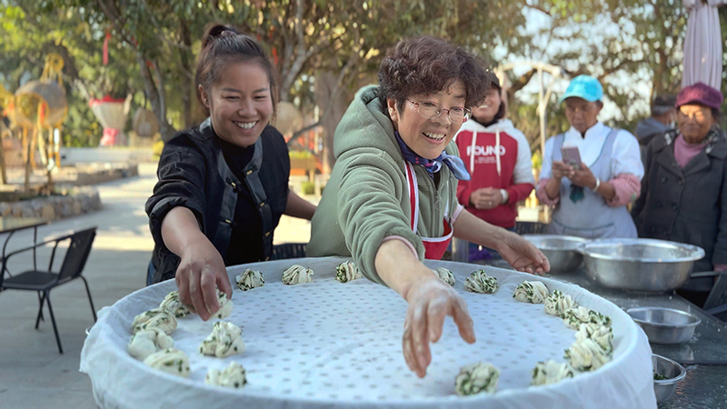【2】旅居者趙發(fā)英（圖左二）教曼海村村民做花卷。陶思源-攝